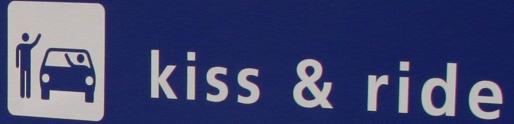 Verkeersbord met pictogram en tekst 'kiss & ride', dat een korte stopplaats aanduidt voor het in- of uitstappen van passagiers.