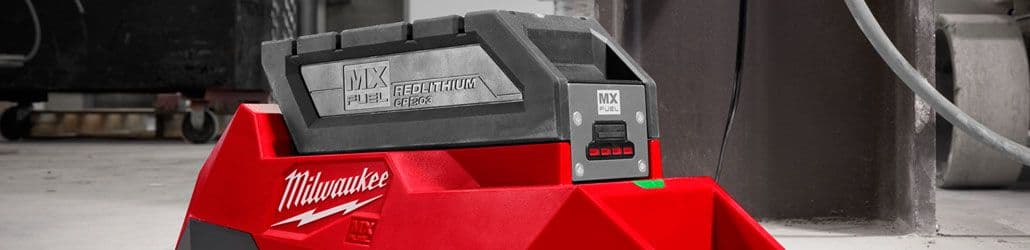 Close-up van een Milwaukee MX FUEL RedLithium accu op een acculader in een industriële omgeving, met zicht op laadindicator en robuust ontwerp.