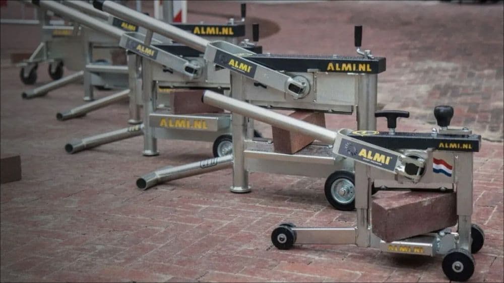 Rij aluminium ALMI steenknippers op straat met een baksteen tussen de snijbekken.