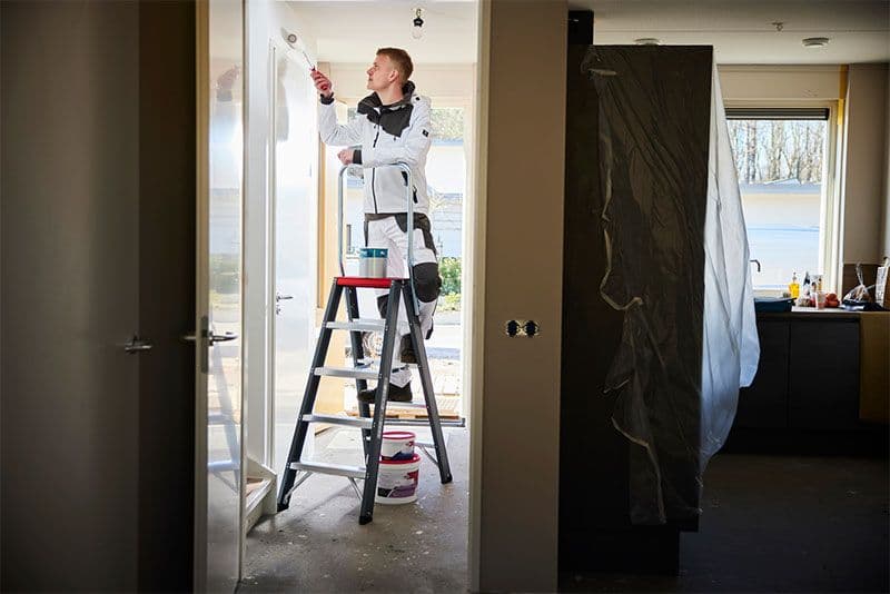 Schilder aan het werk op een trap van Altrex