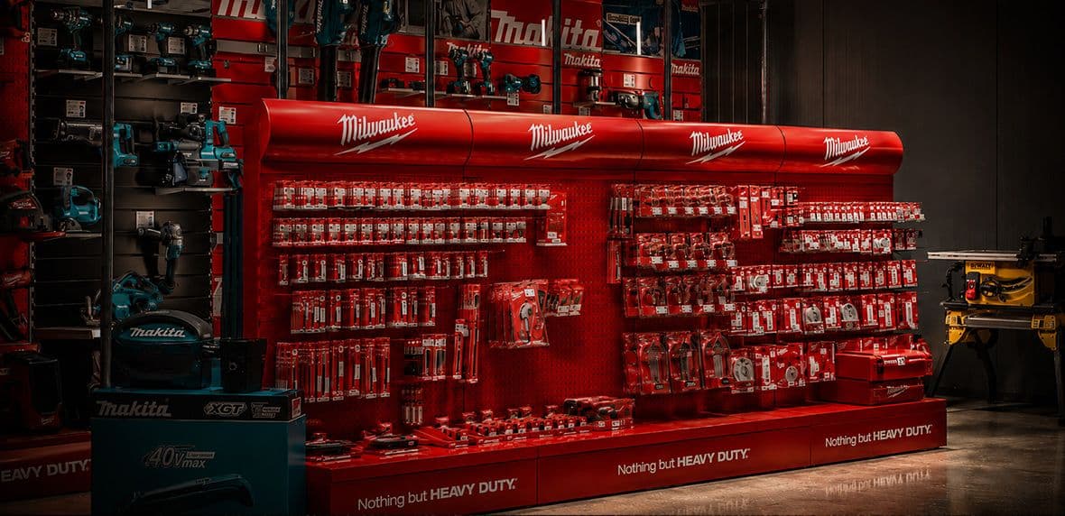 Rode Milwaukee-wand met gereedschapsaccessoires in een bouwmarkt of gereedschapswinkel.