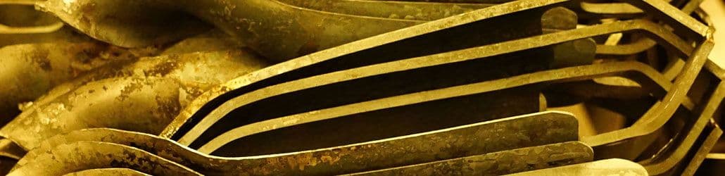 Close-up van meerdere metalen grondboorbladen met een roestige en verweerde afwerking, opgestapeld in een industriële omgeving.