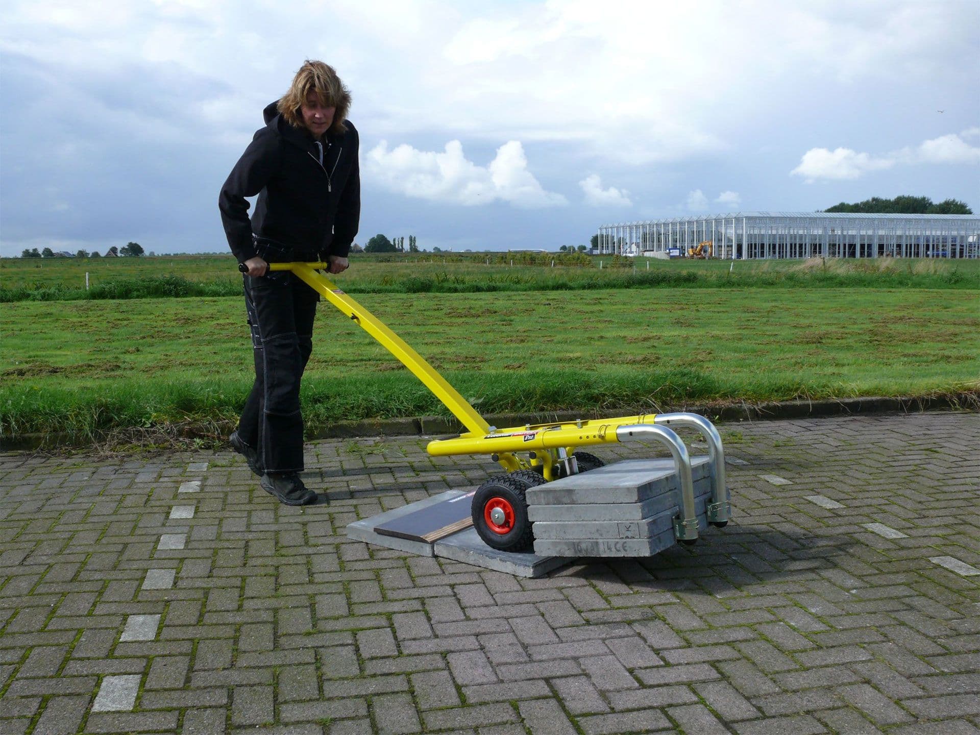 Vrouw met TessPaver die een stapel zware tegels verplaatst