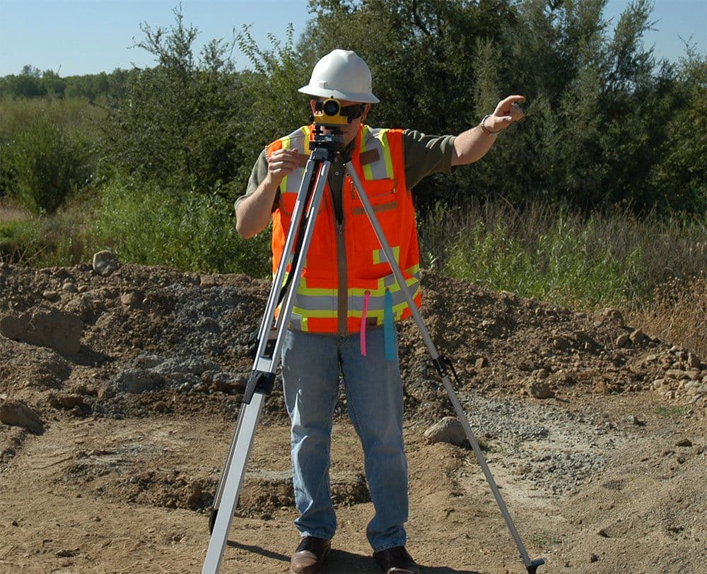 Man met waterpasinstrument in de rimboe