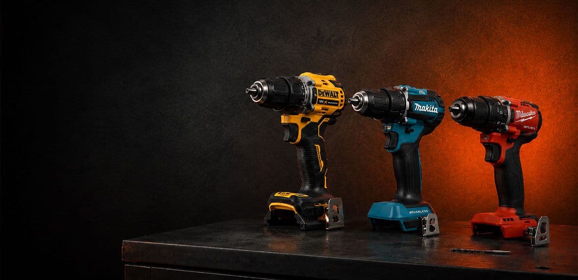 DeWalt, Makita, Milwaukee boormachines op een tafel met zwart oranje achtergrond.