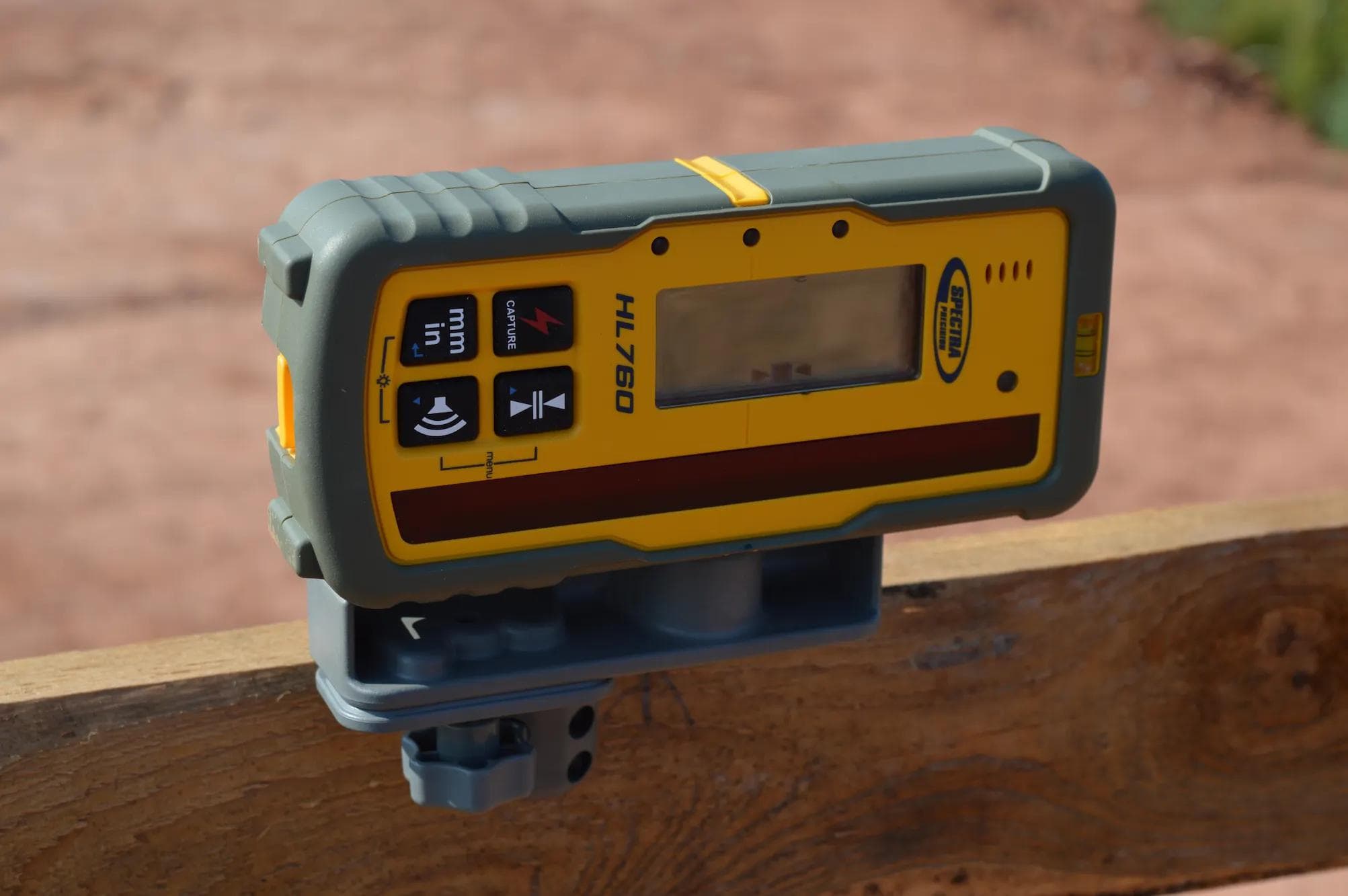 Spectra HL760 laserontvanger met display en knoppen op statief op houten oppervlak.