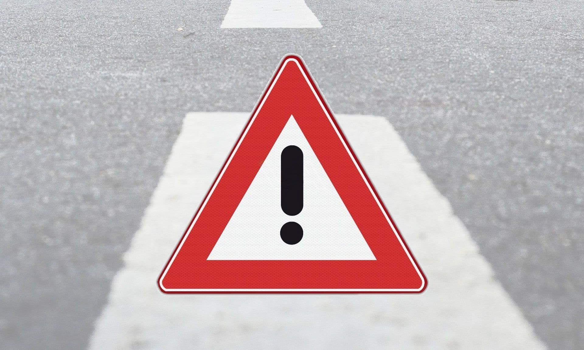 Verkeersbord Uitroepteken J37 op een zwarte asfaltweg