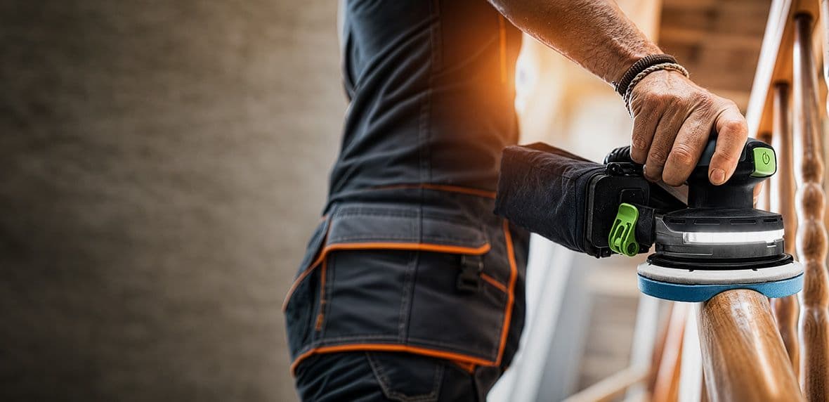 Man met Festool schuurmachine en Granat schuurschijf werkende aan een houten trap.