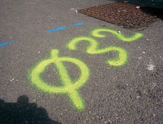 Gele markering met symbool en getal “⌀32” op asfalt, aangebracht met krijtspray als tijdelijke aanduiding voor ondergrondse infrastructuur.