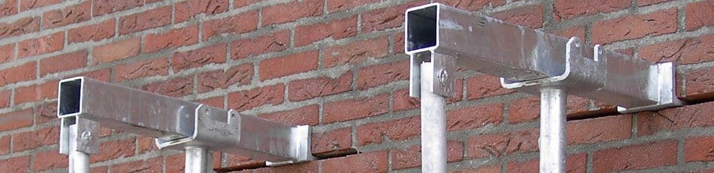 Twee metalen geveldragers van het type Stutalone gemonteerd tegen een bakstenen muur, gebruikt voor het tijdelijk ondersteunen van metselwerk.